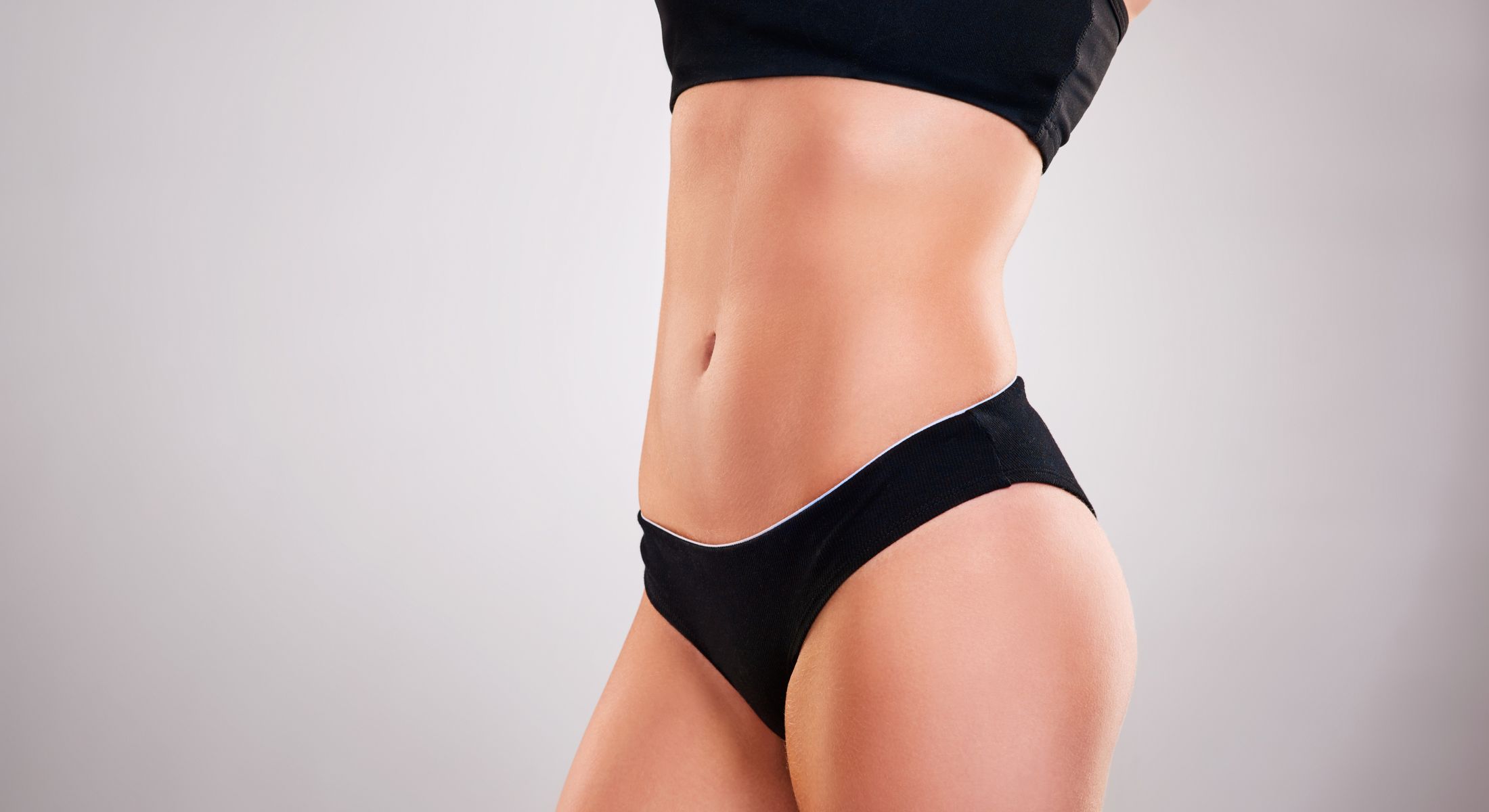 Athletic woman in black sportswear displaying abs